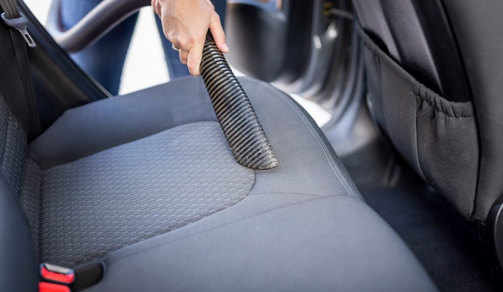 Woman vacuum cleaning car seats